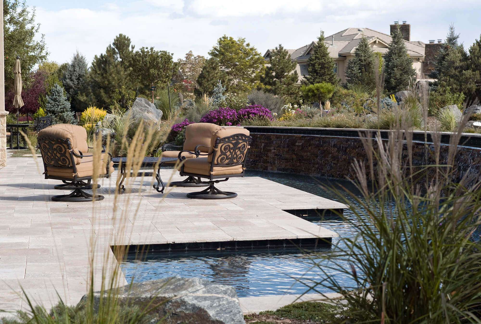 Backyard area with some chairs, tables, and swimming pool