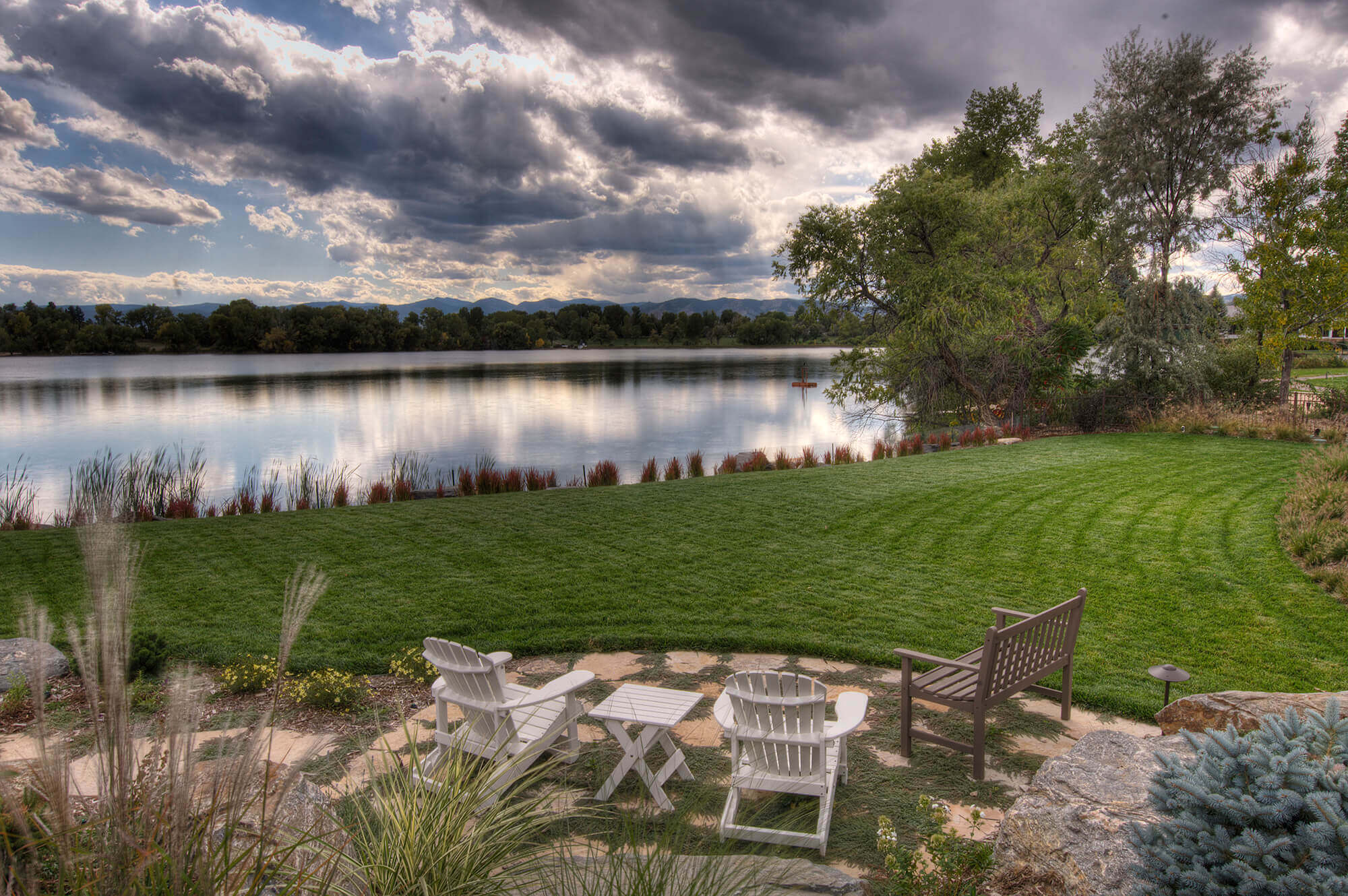 Backyard area with some chairs, table, and beautiful lake view