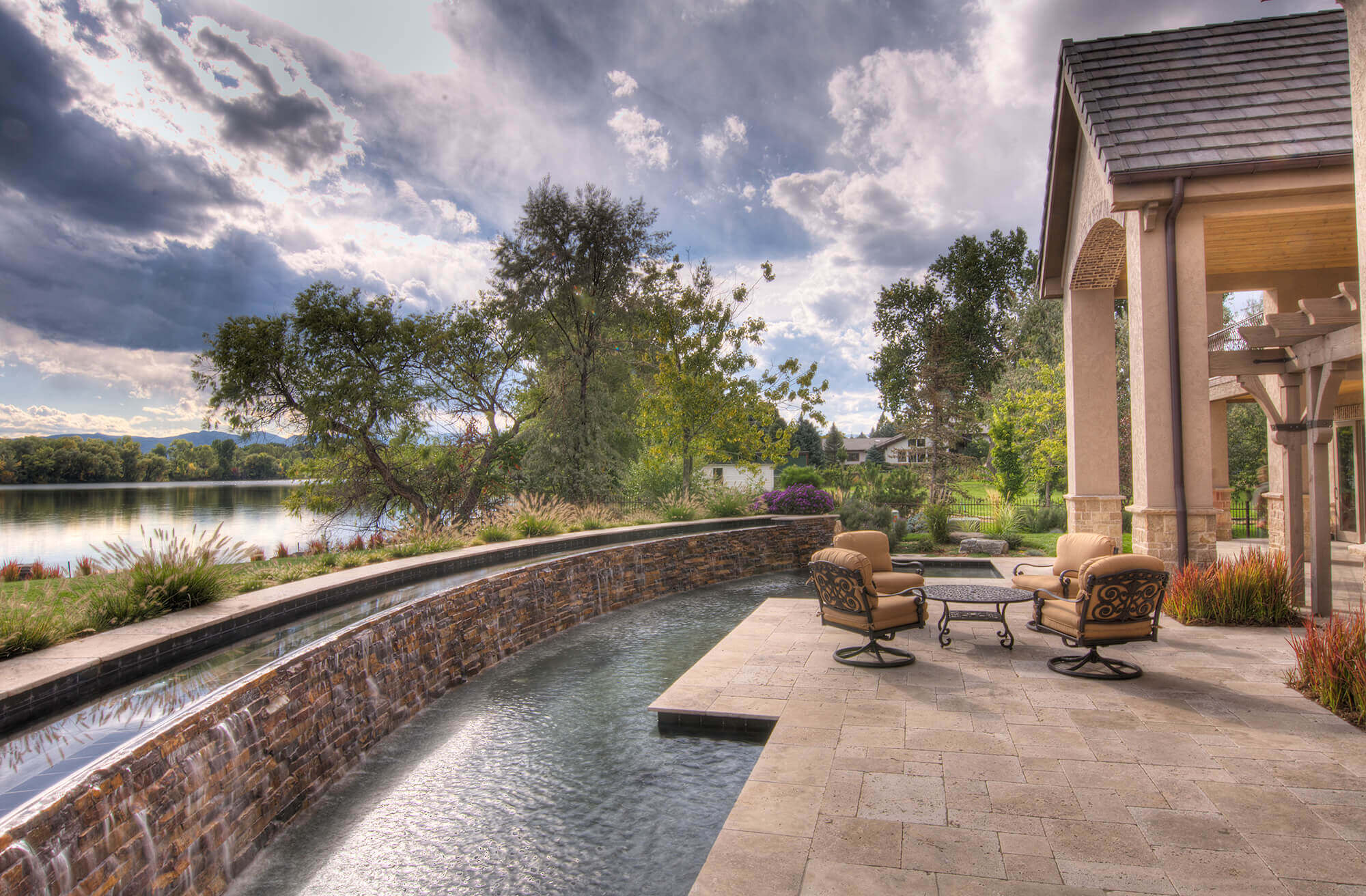 Backyard area with some chairs, tables, swimming pool and a beautiful view of the sky