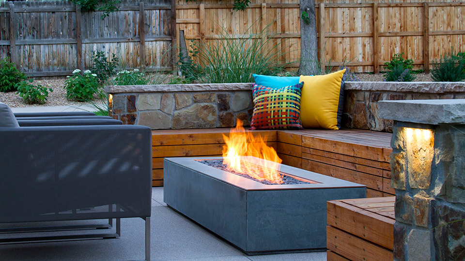 Fire pit surrounded by wooden sofa and chairs in the backyard