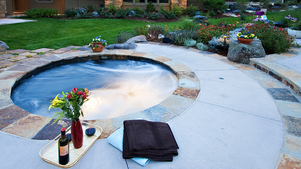 A small pool along with wine , flower vase and towels in the back yard