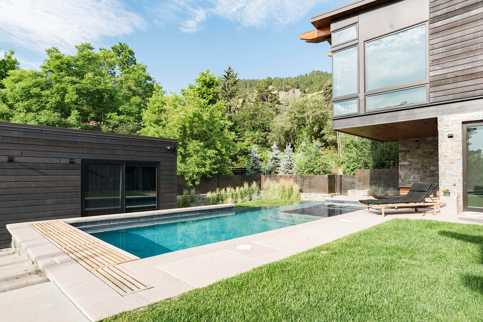 Backyard area with some relaxing chairs and swimming pool and guest house