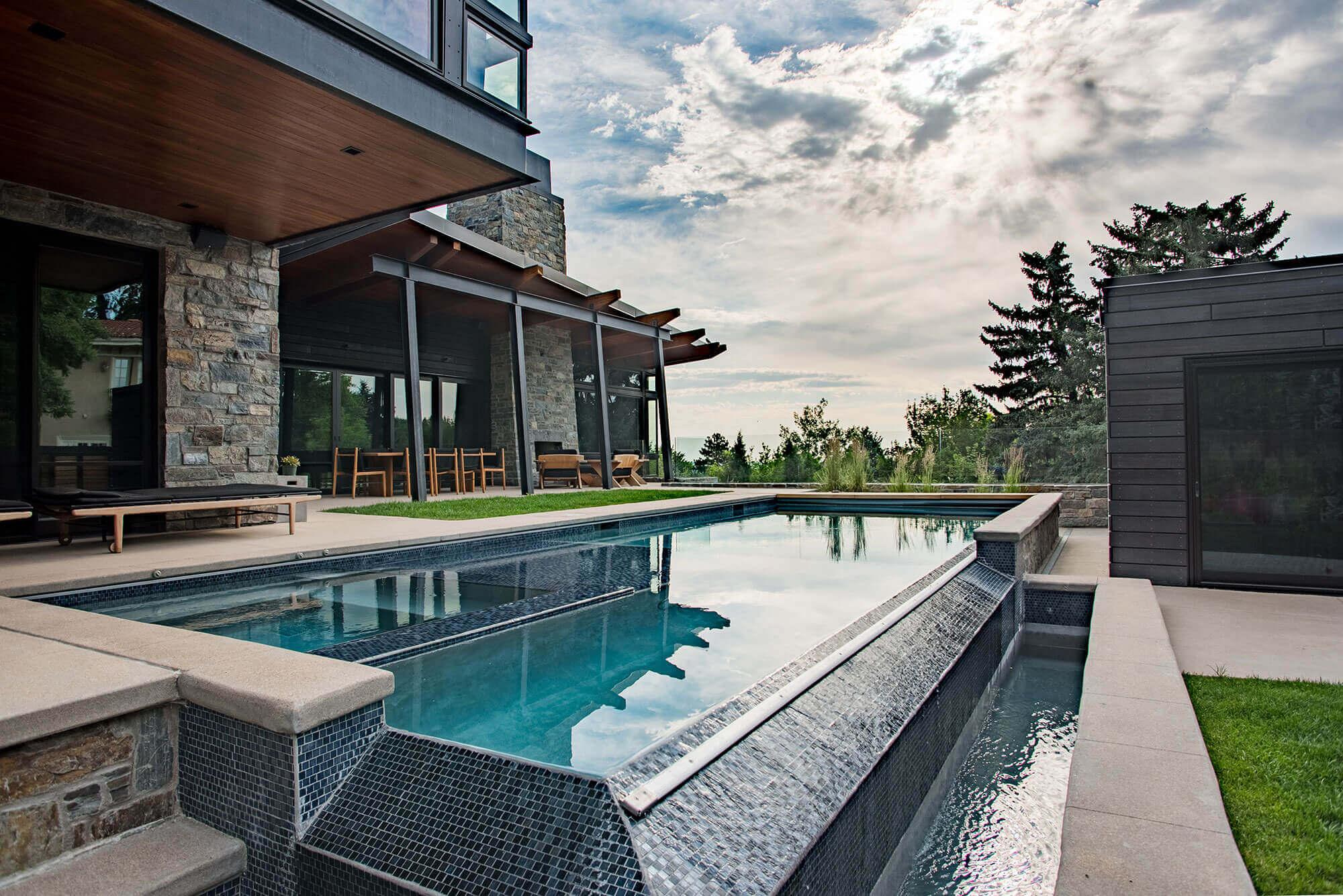 Backyard area with some relaxing chairs and swimming pool and guest house