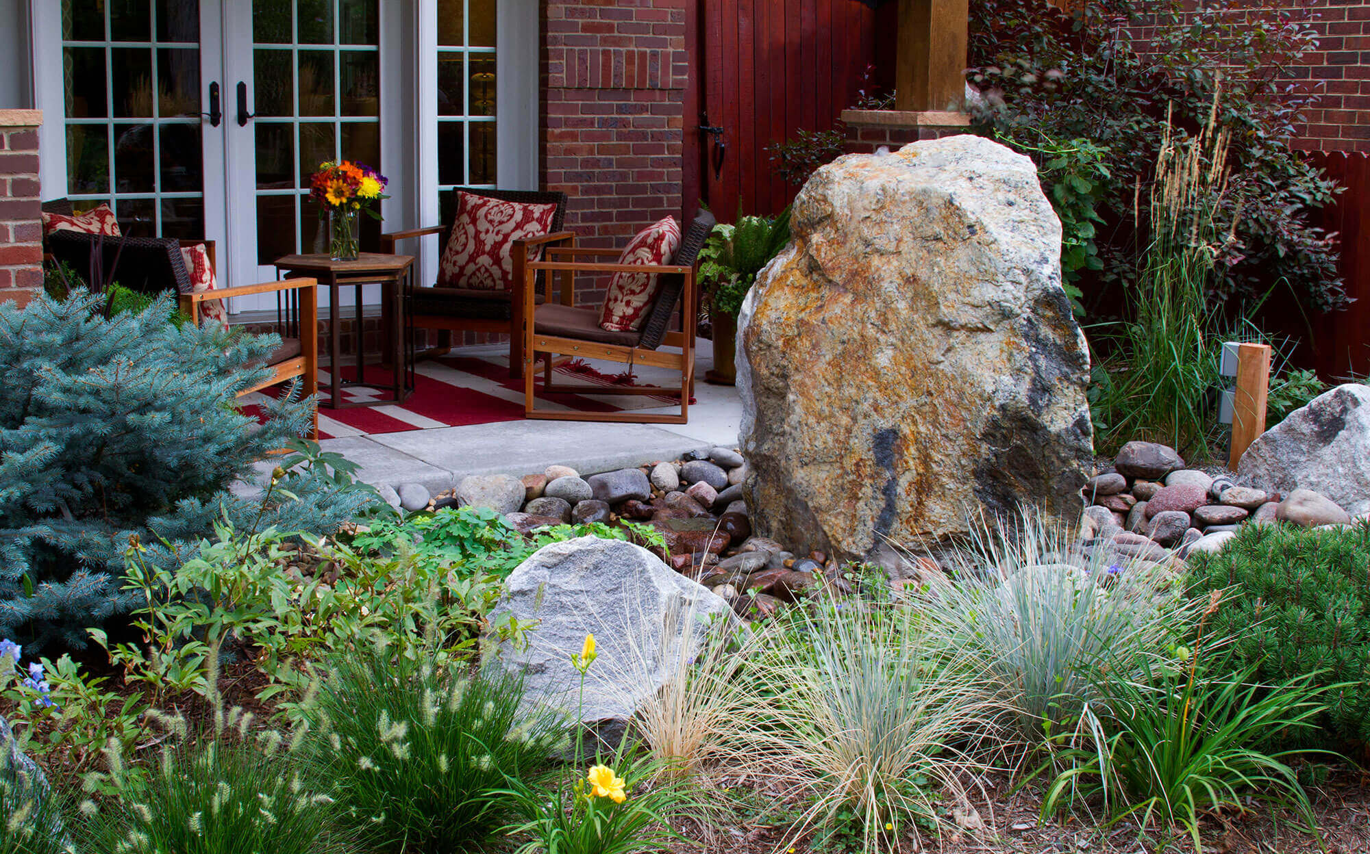 Backyard with chairs around the table with grass plants and rocks