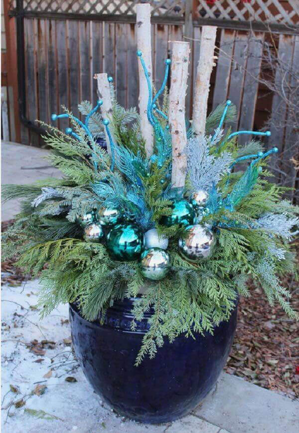 A plant is decorated with christmas bulbs in front of the house