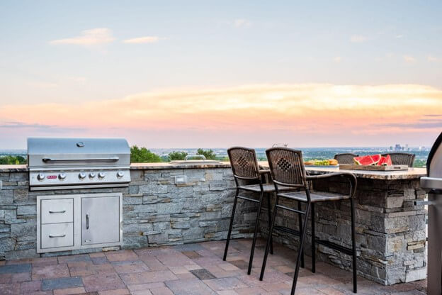 Stone Outdoor Kitchen Featuring a Bar Overlooking a Vista