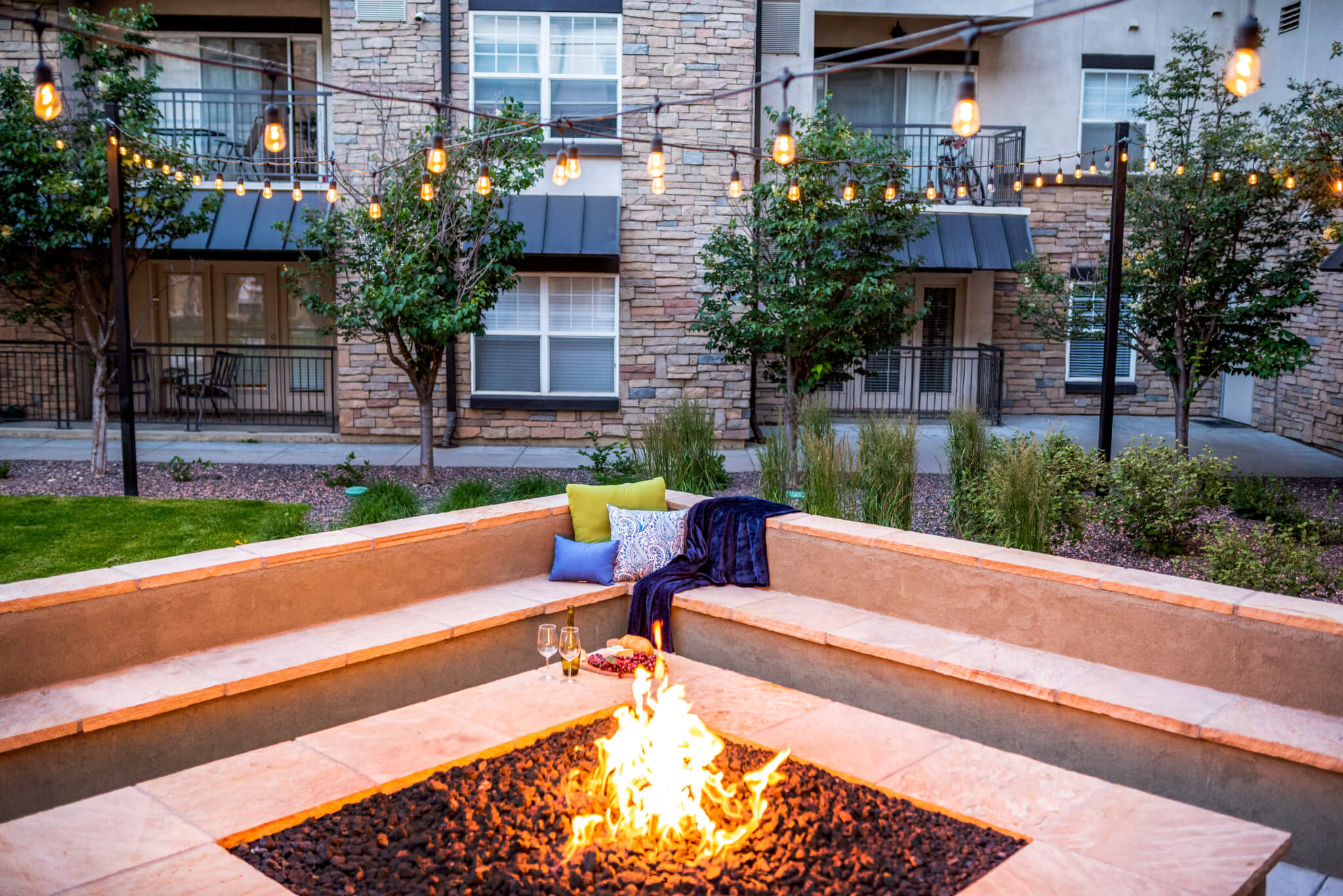 Fire pit in a courtyard area with plants and lights