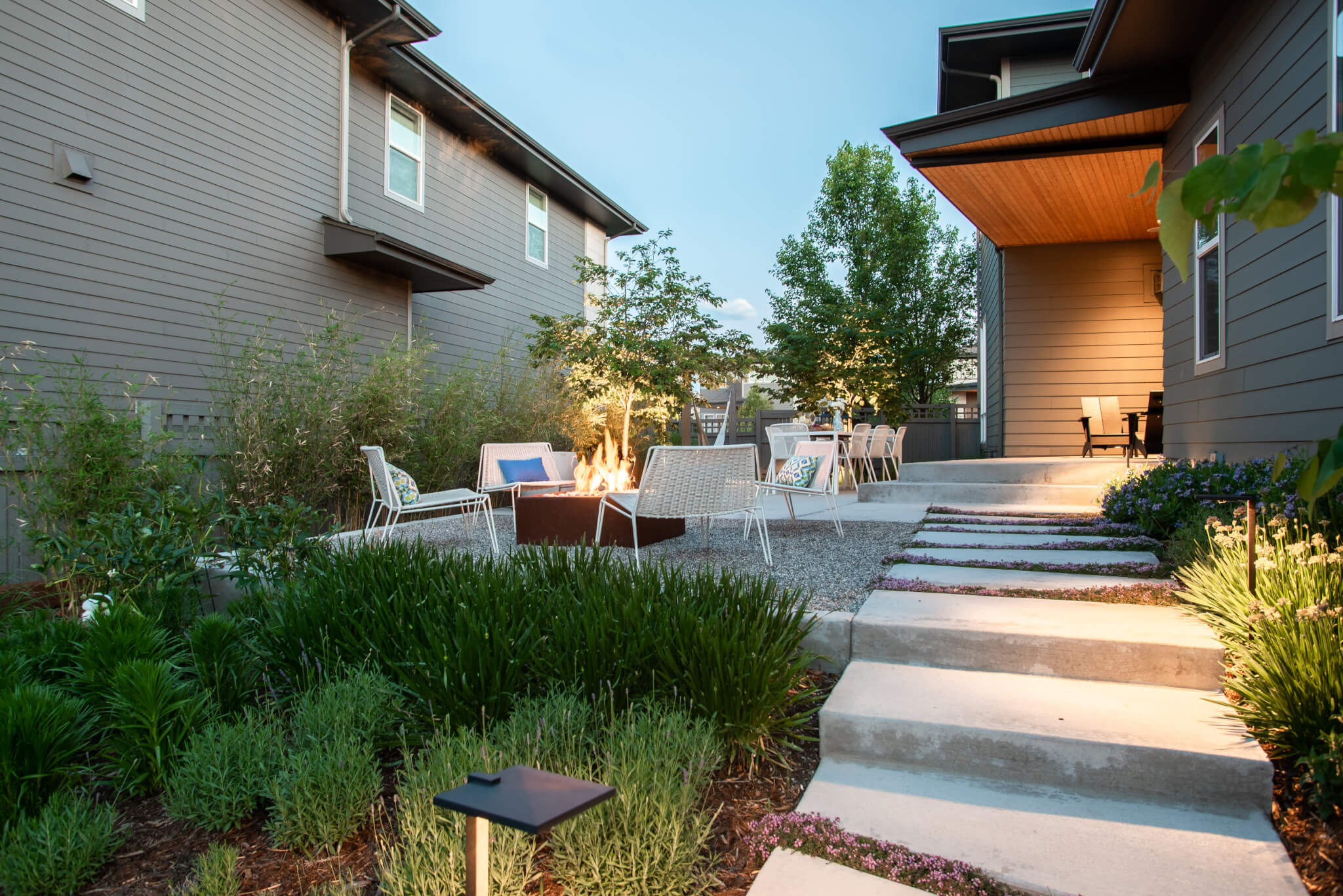 Backyard along with fire pit, chairs, dining table, plants and trees