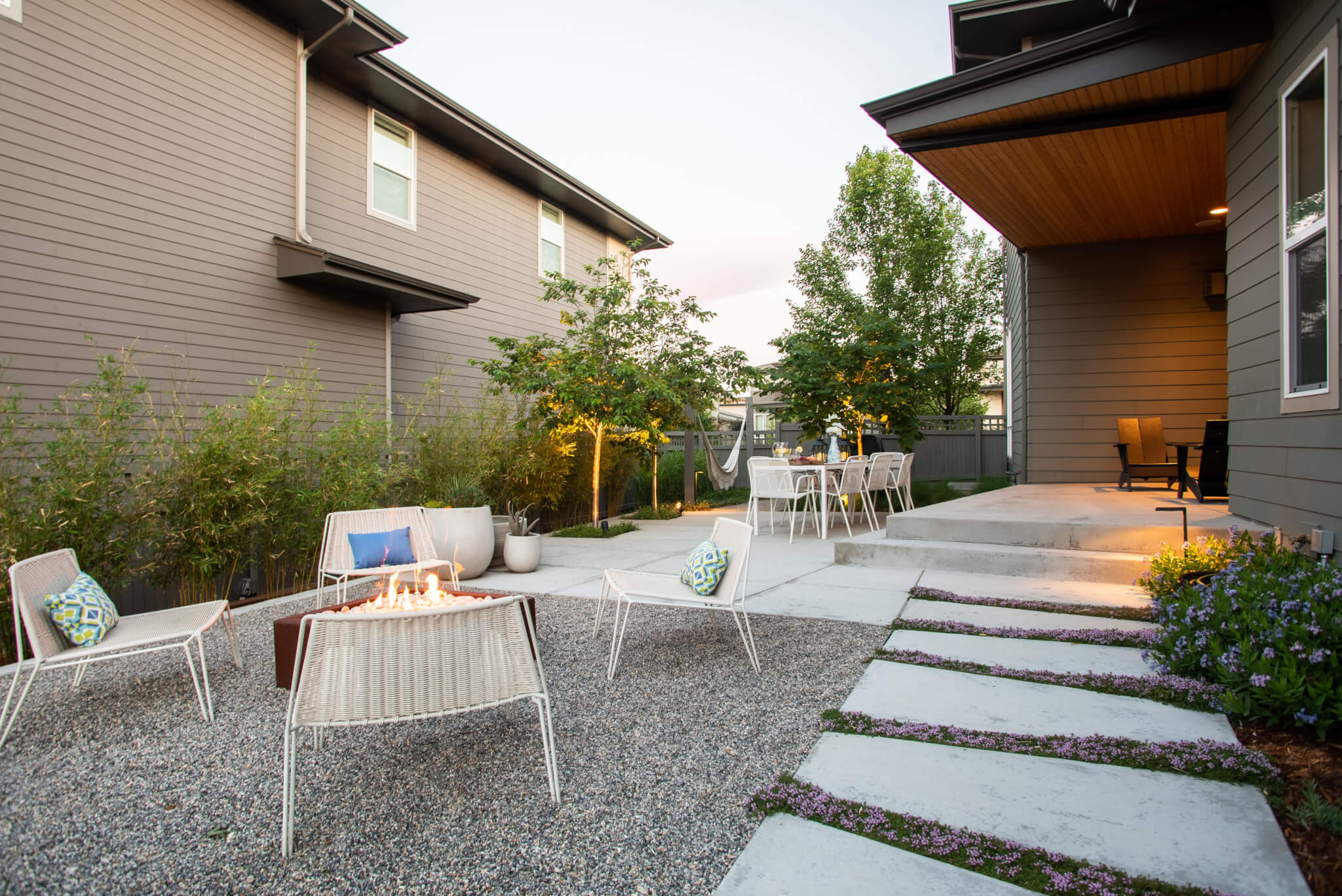 Backyard along with fire pit, chairs, dining table, plants and trees