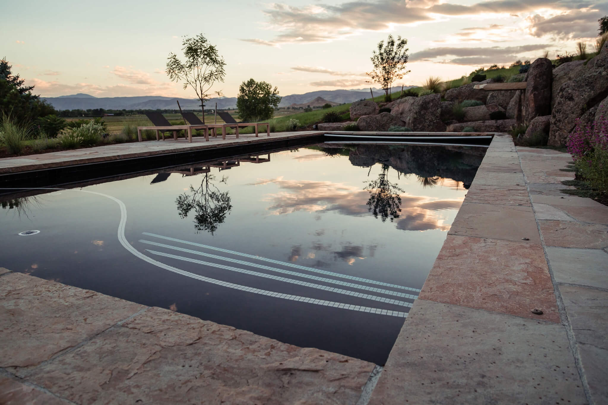 Pool area with relaxing chairs along with sky view