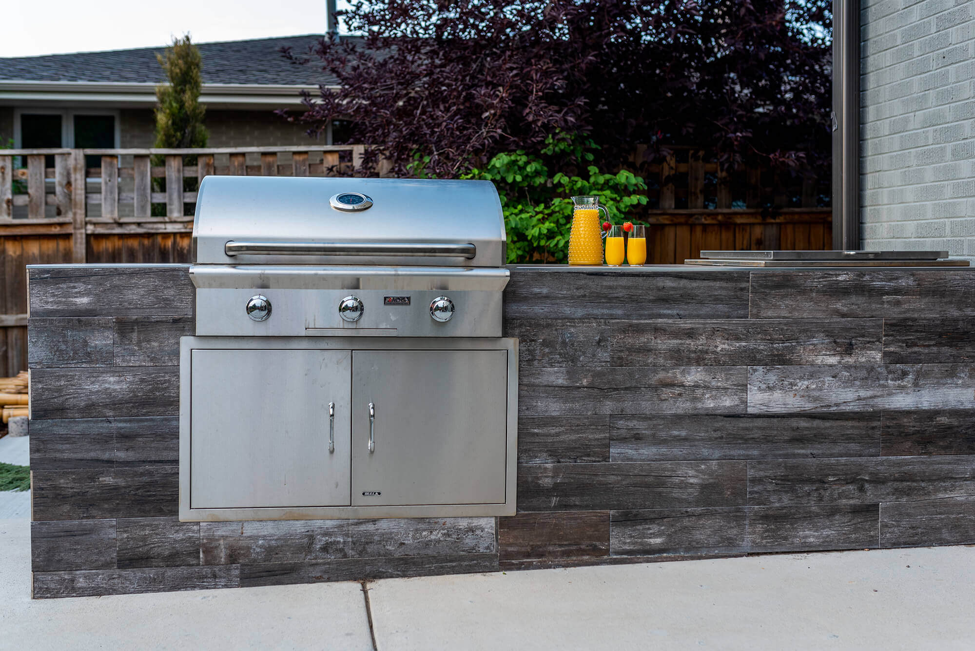 Outdoor kitchen area with a pitcher of juice and 2 glass cups