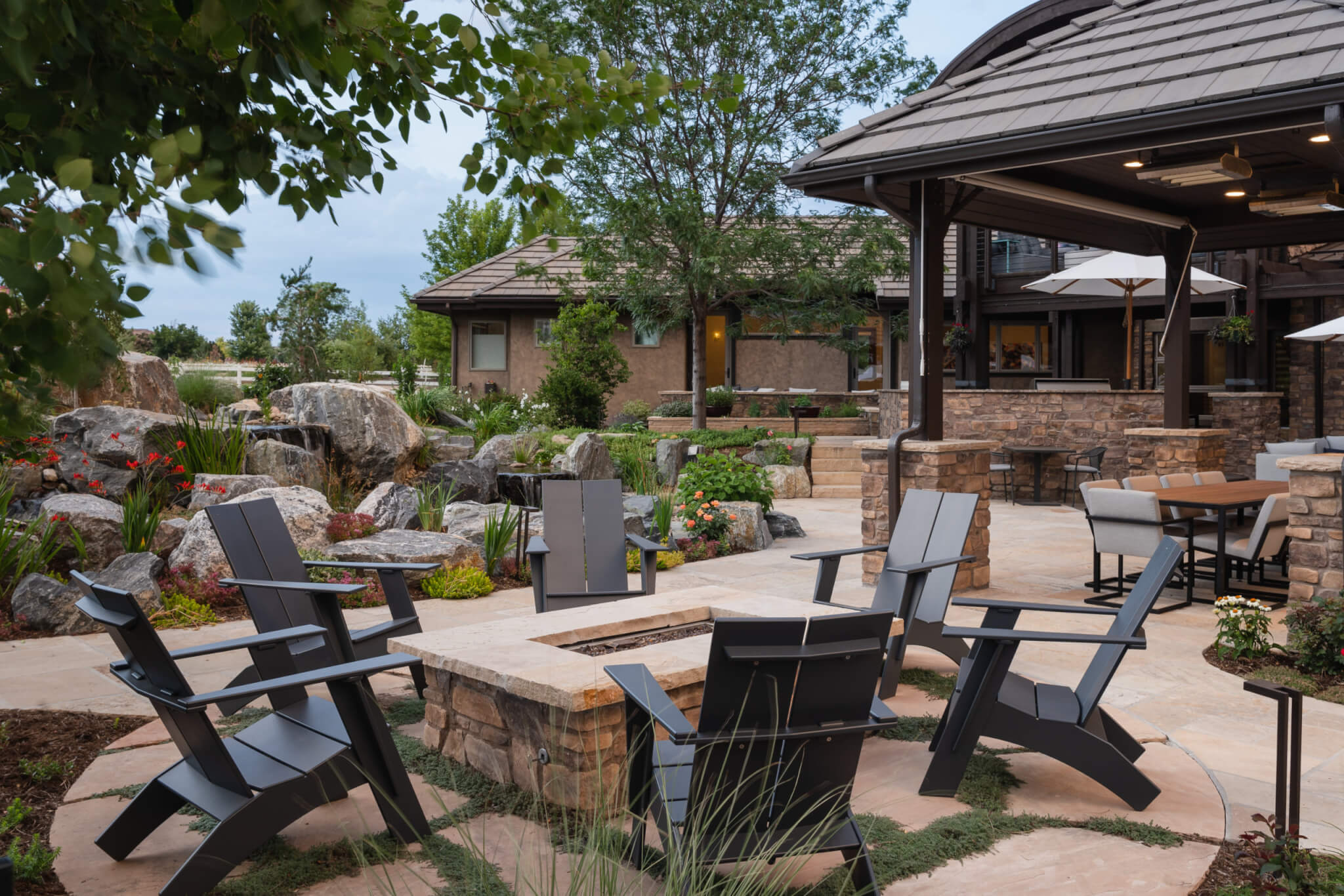 View of a backyard showing gazebo, firepit, chairs plants, and a pathway