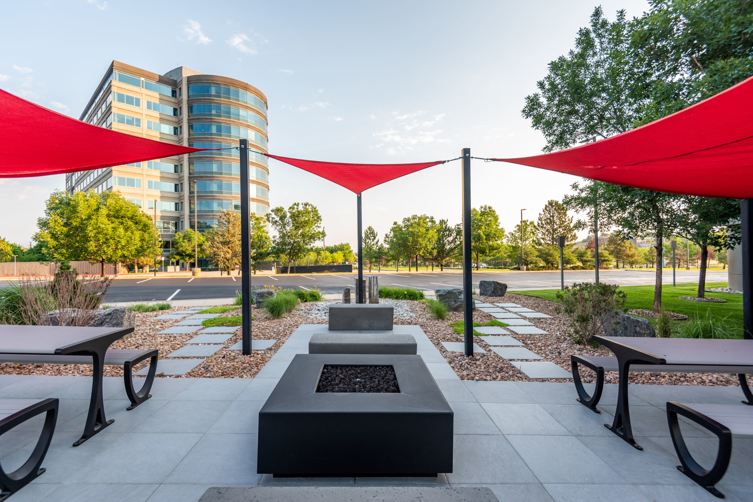 Sitting benches with red fabric tensile membrane with sail shade structure in front of the building