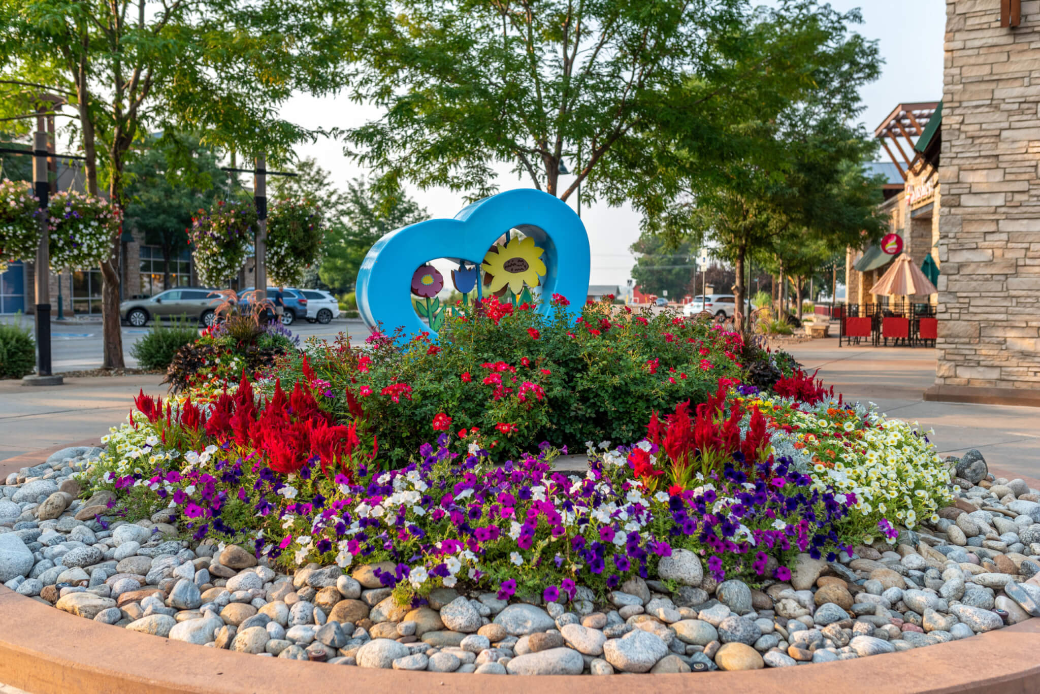 colourful flower plants and plants along with blue coloured love symbol statue on the road