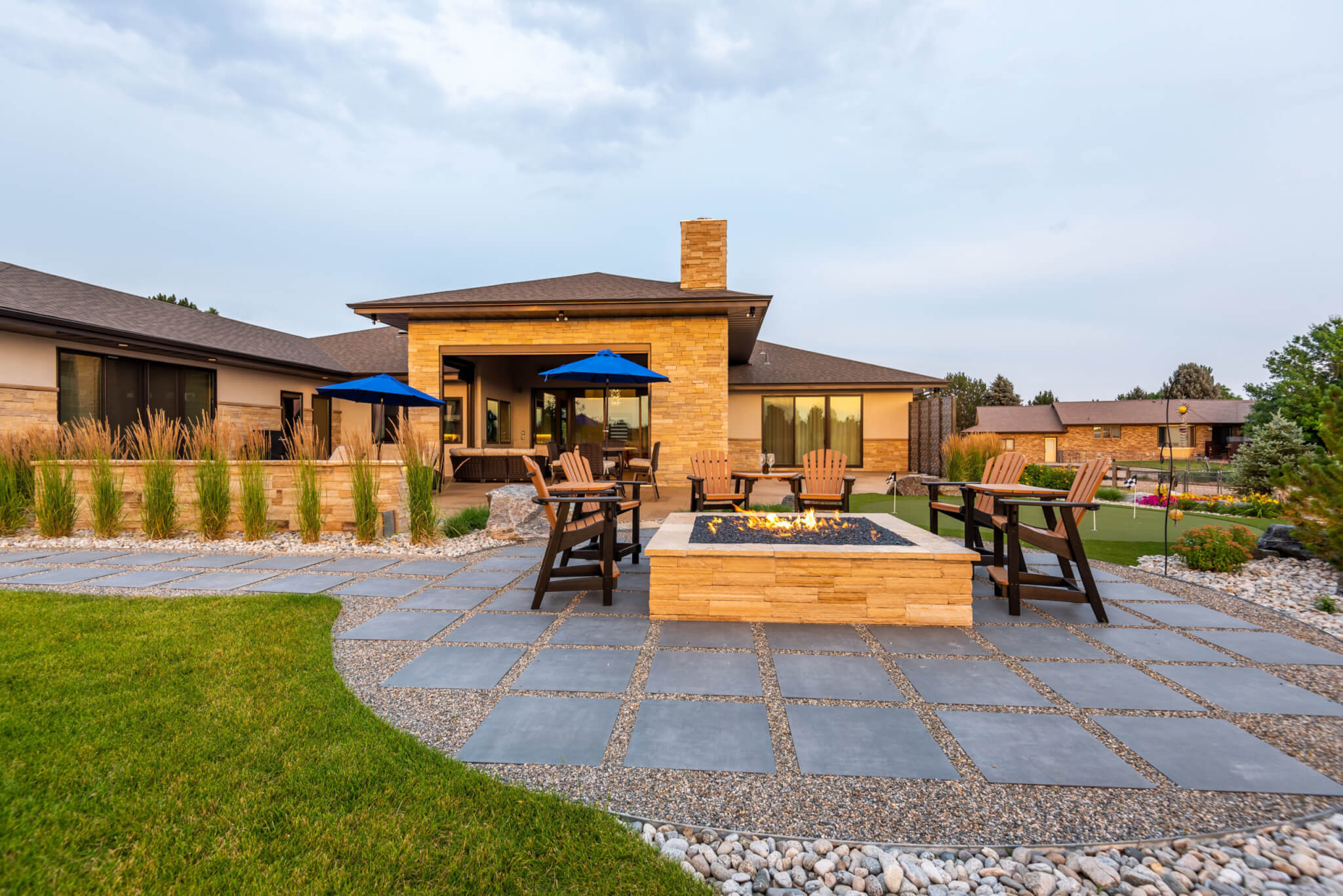 Backyard view from garden area filled with chairs around the fire pit