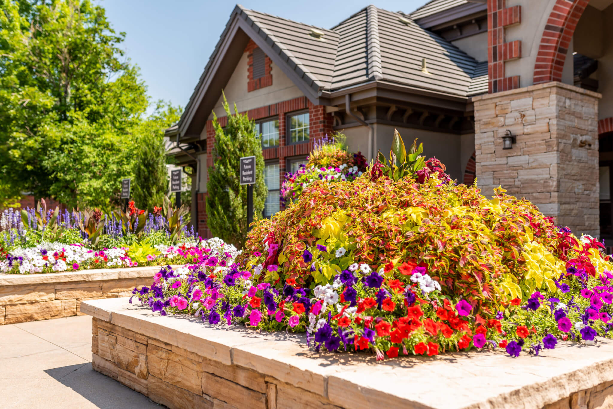 Stacked stone flower pots filled with different types of plants and colourful flower plants in front of a buildings