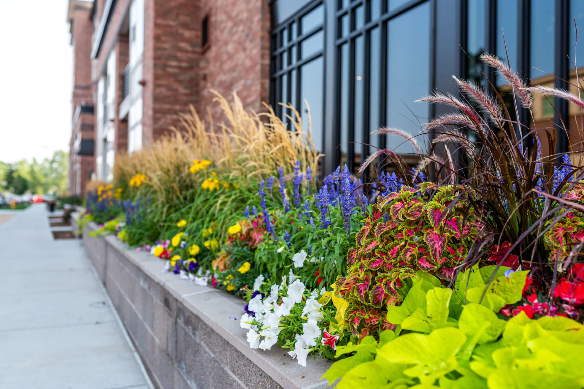 Stacked stone flower pot is filled with Different colour flower plants out side of a building