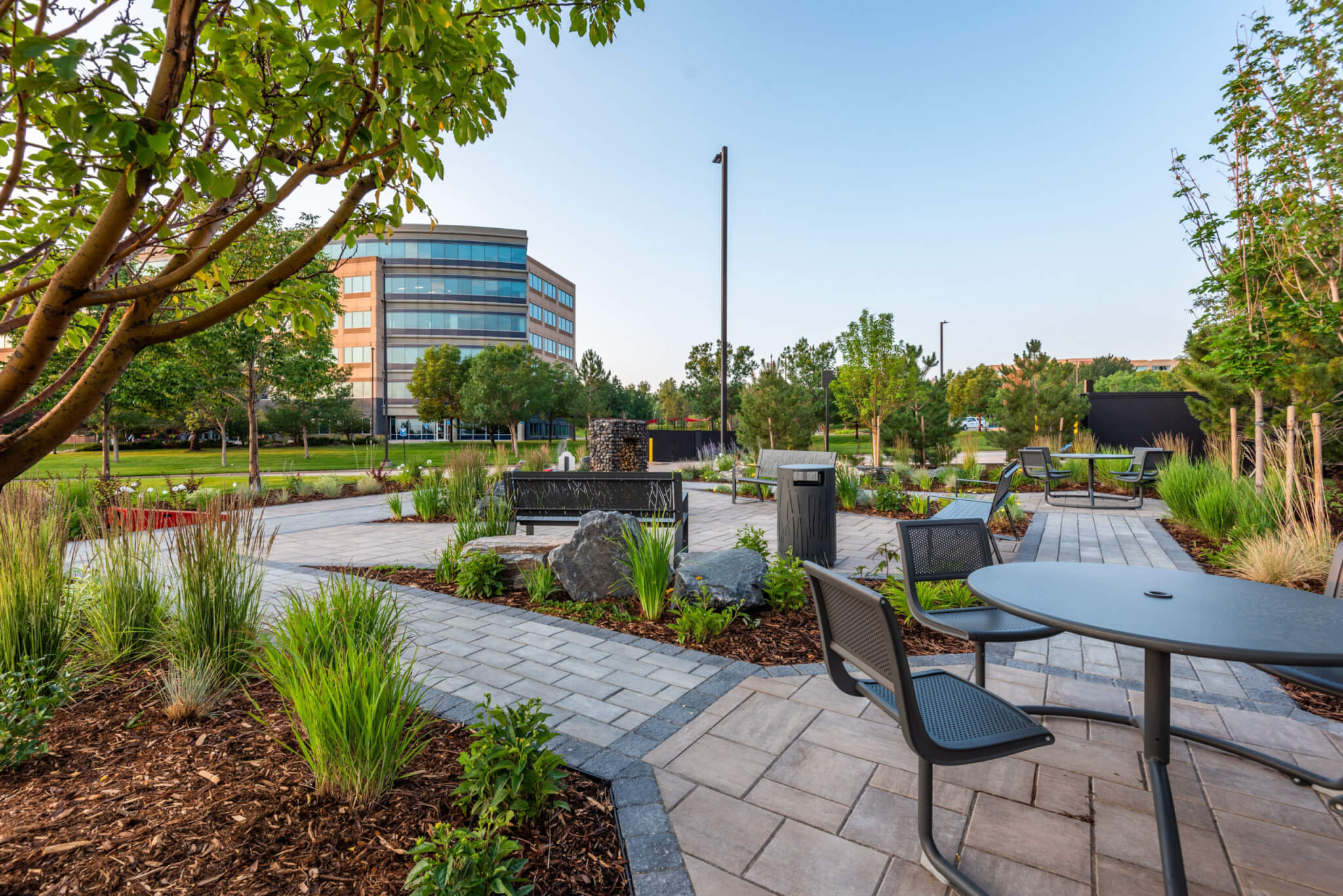 Tables and Chairs setup in a lawn with plants and trees outside a building