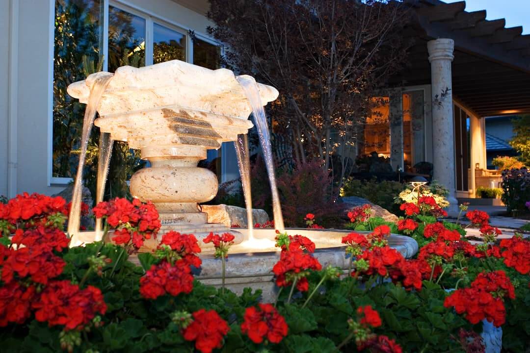 Lighted Outdoor Fountain Surrounded by Flowers