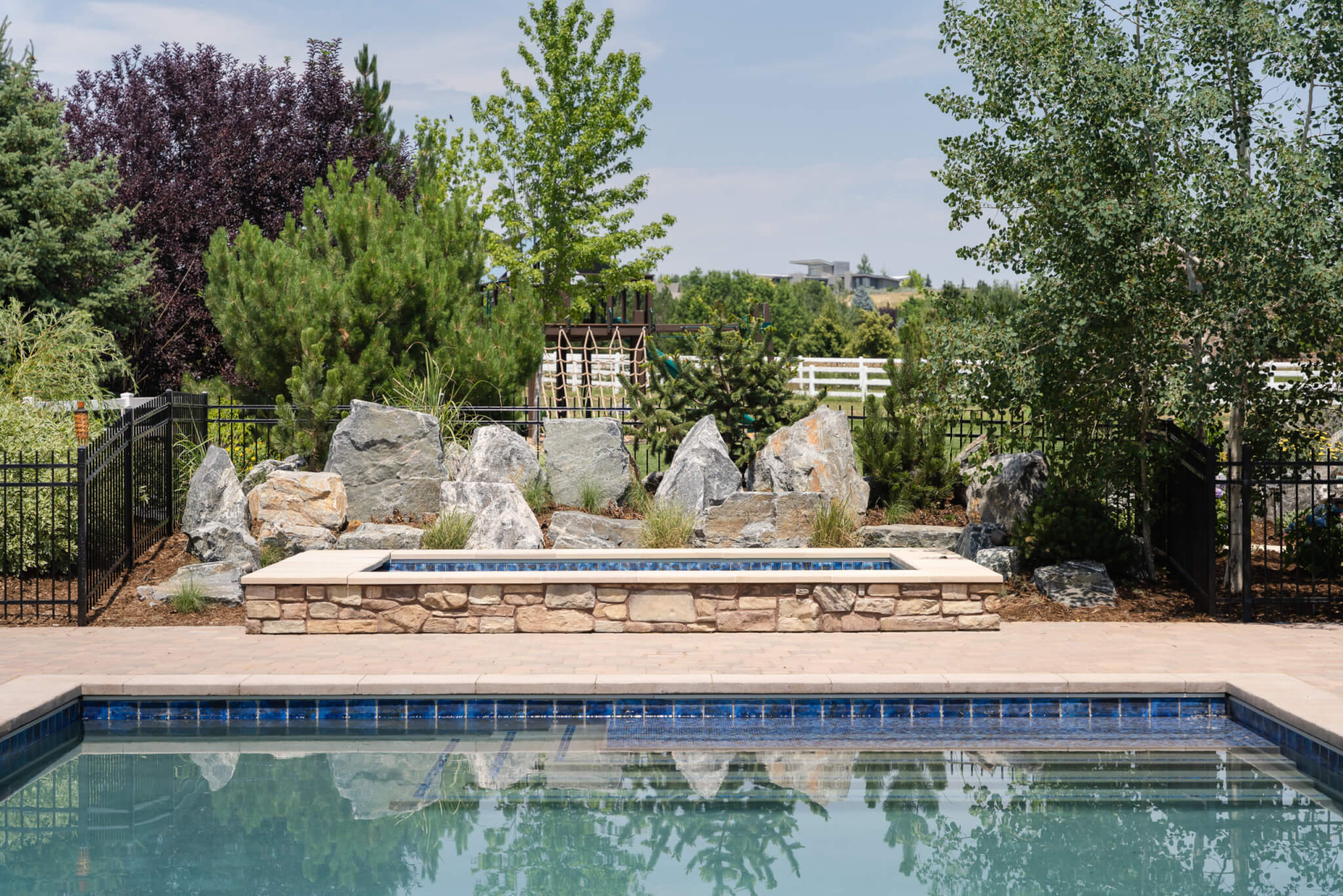 Swimming pool area with stones, plants and trees