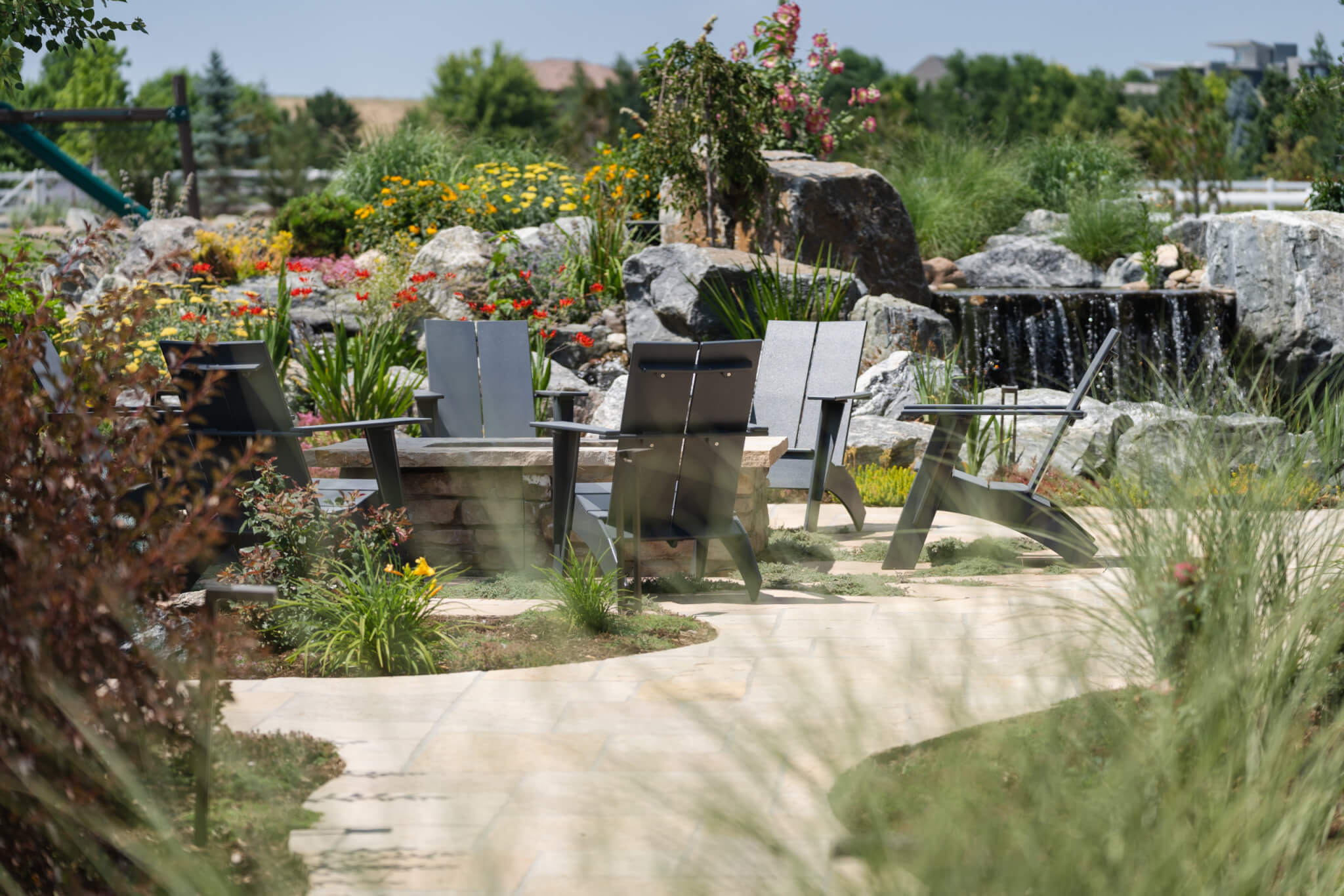 Man-made constructed mini water fall, chairs around fire pit in the backyard