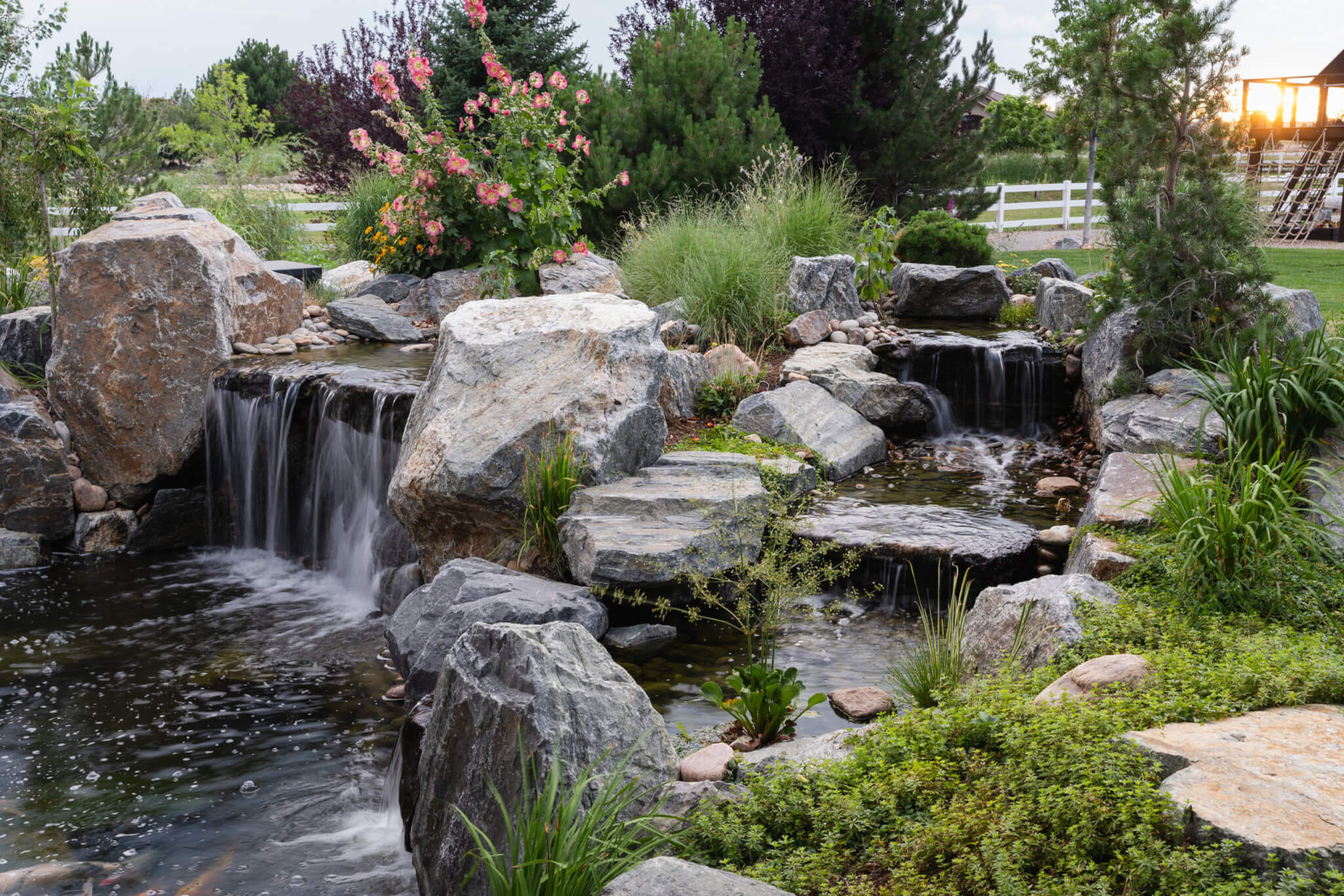 Koi fish pond with a man-made constructed mini waterfall with plants and trees