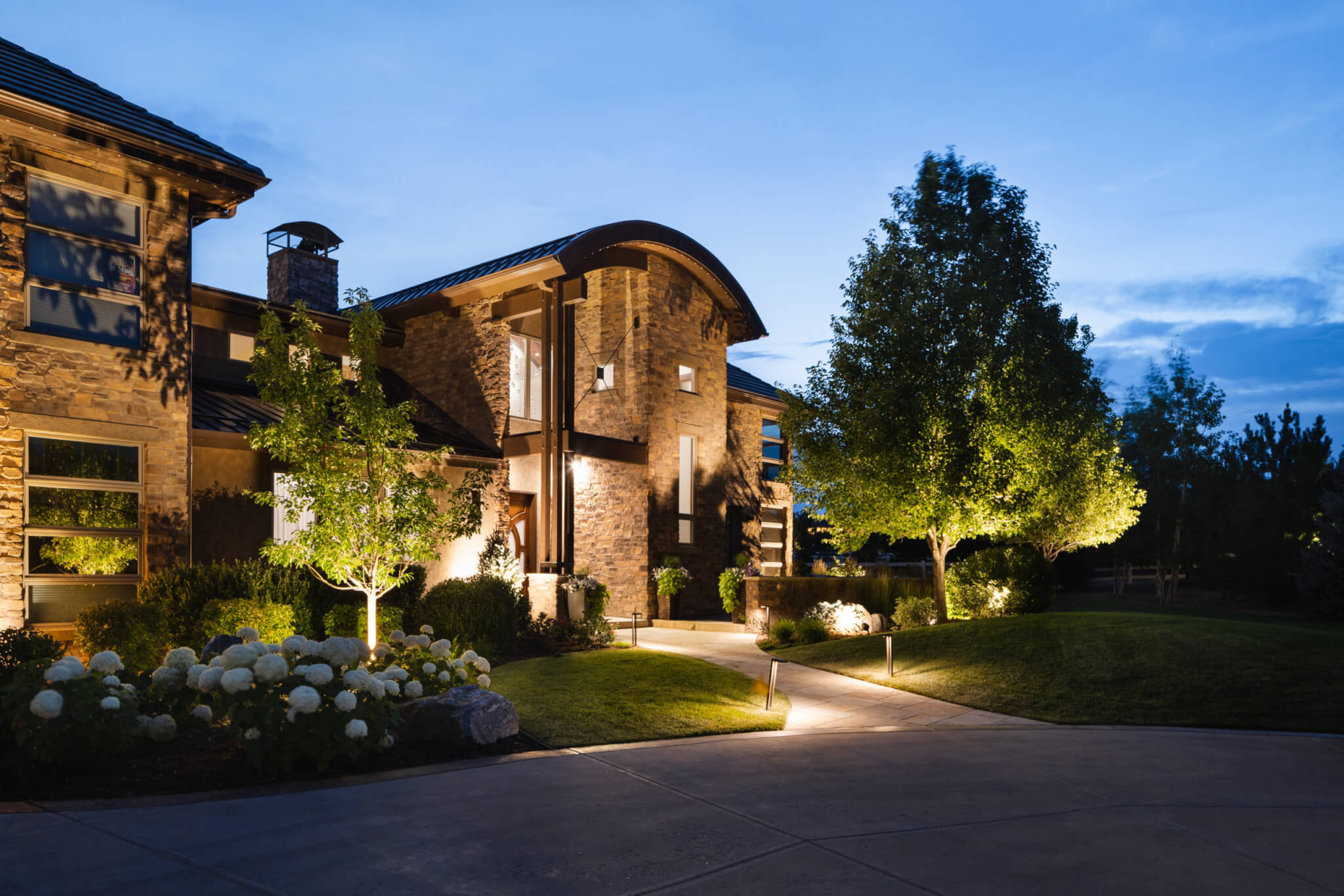 Front view of a house with flower plants, trees and pathway