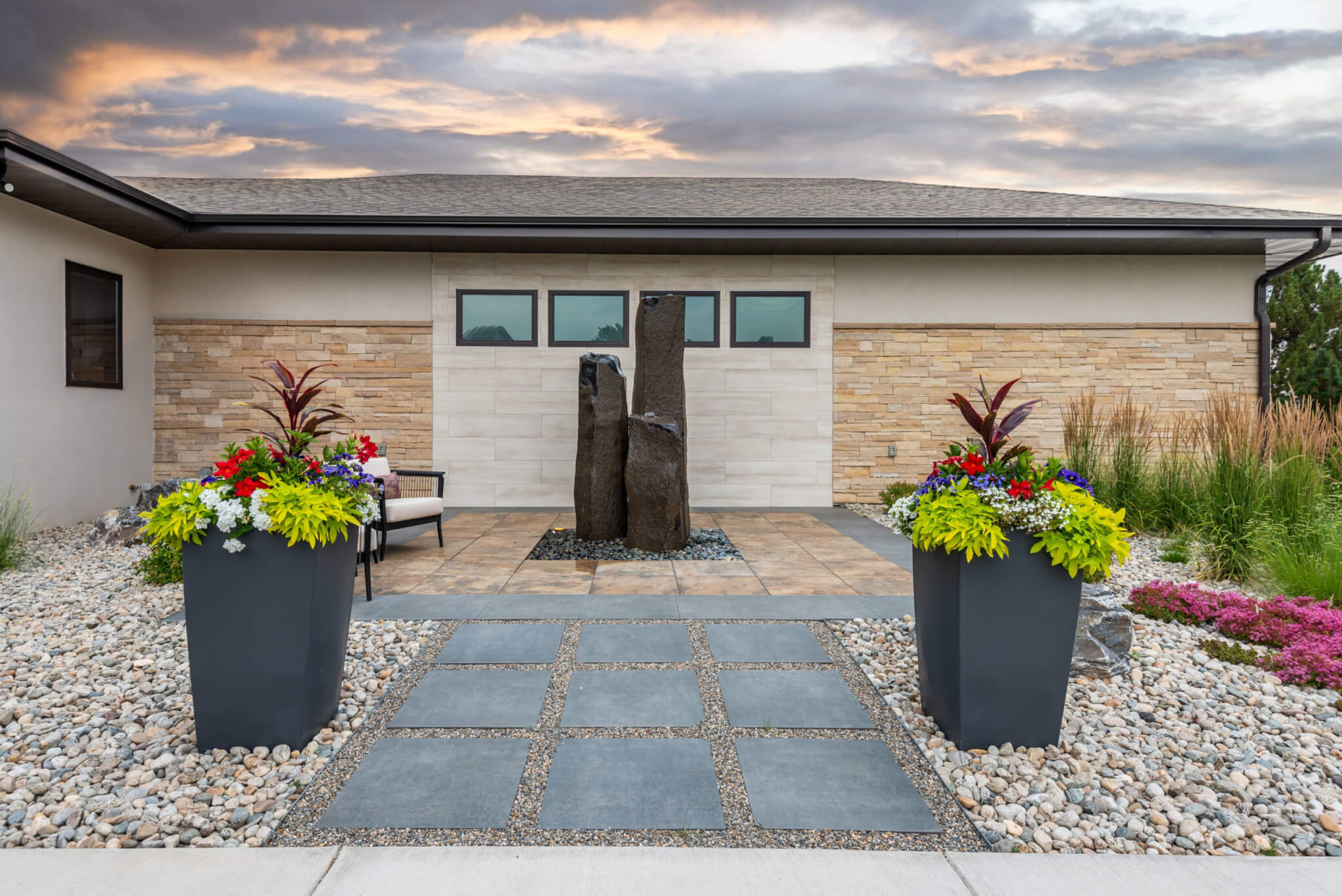 Rock sculpture in backyard area with flower plant pots and grass plants