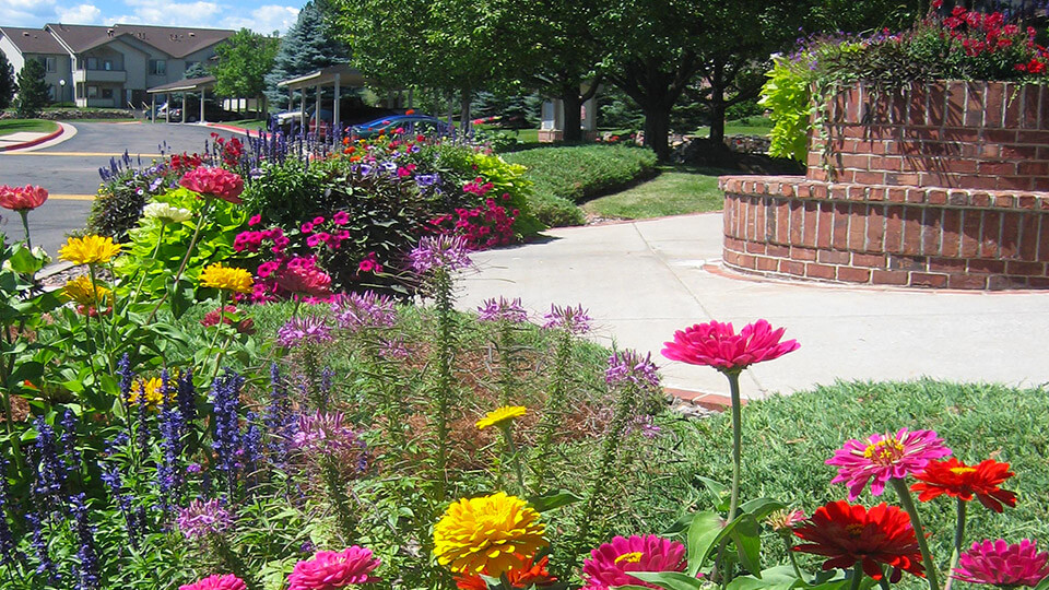 The junction in the road has stacked stone flower pot and different types of flower plants around it