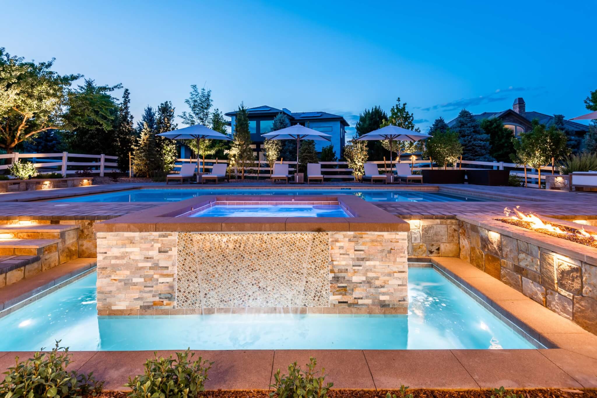 Backyard with Swimming pool, fire pit along with chairs, umbrellas, plants, and trees