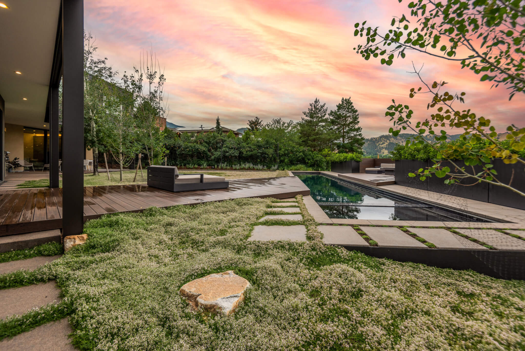 Backyard of the house with some relaxing sofas, swimming pool and a beautiful sunset view outside