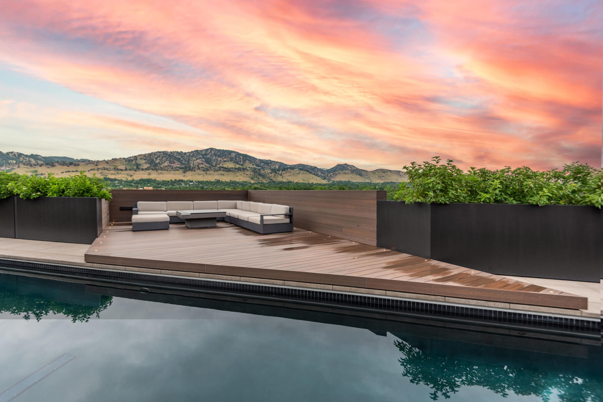 L shaped sofa outside with a swimming pool with a view of the mountains and orange sky