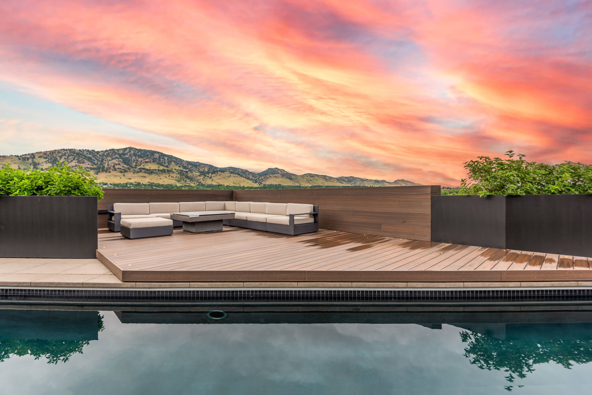 L shaped sofa outside with a swimming pool with a view of the mountains and orange sky