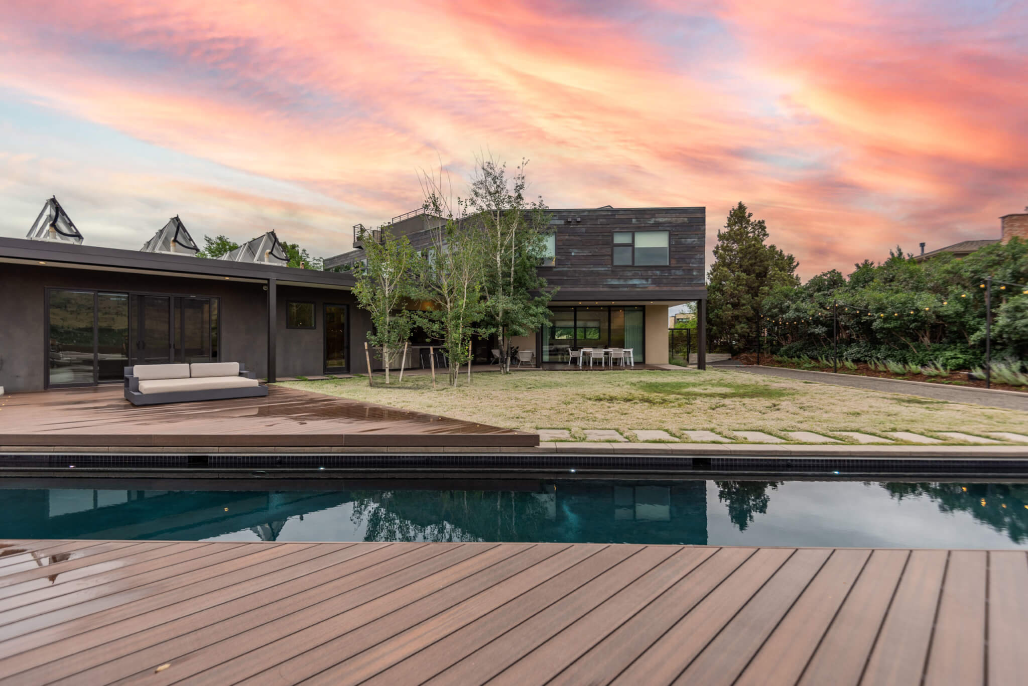 view of the backyard with a pool, lawn area, trees, lights, and a sofa, as well as a sitting area