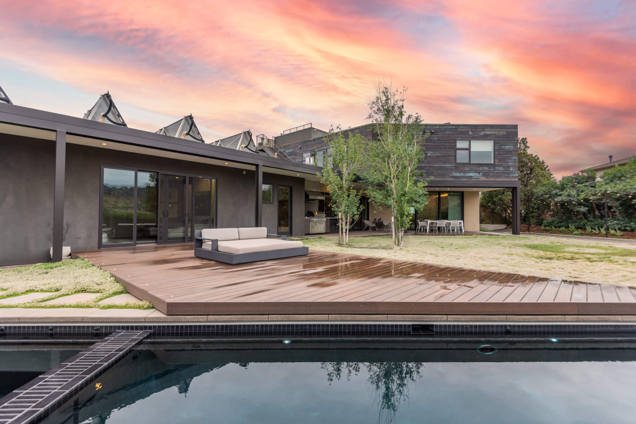 view of the backyard with a pool, lawn area, trees, lights, and a sofa, as well as a sitting area