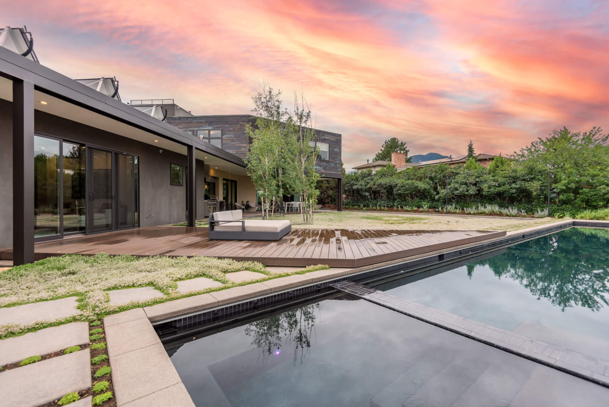 view of the backyard with a pool, lawn area, trees, lights, and a sofa, as well as a sitting area