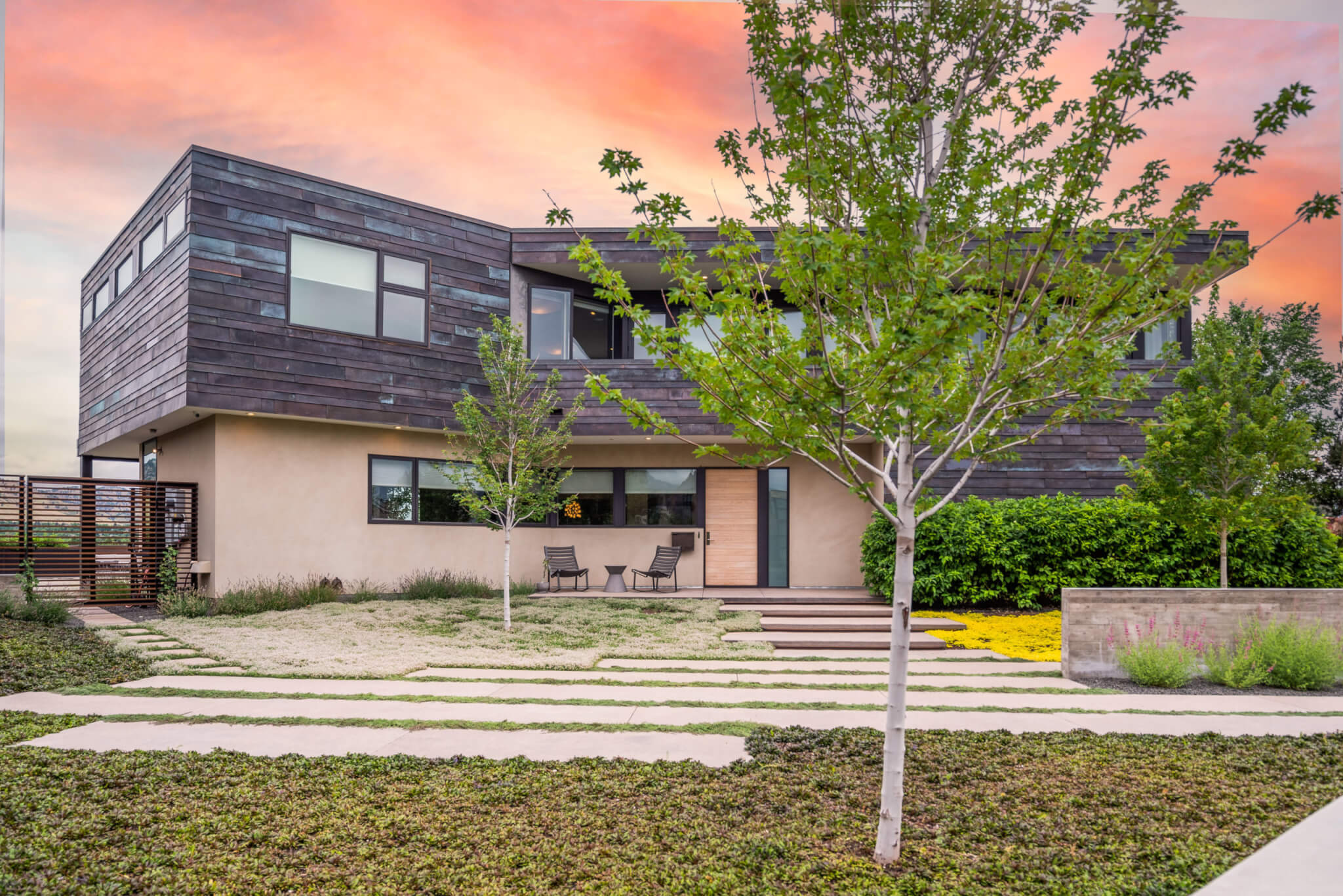 Front view of a house with tinted glass windows, plants and trees