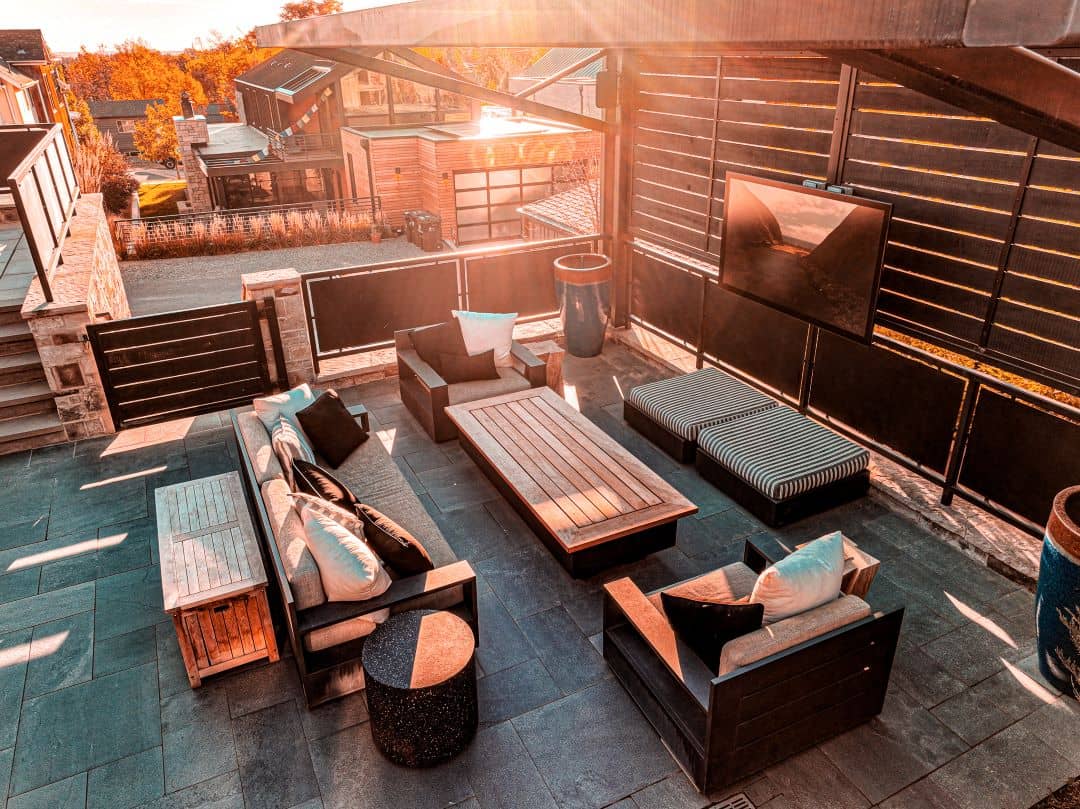 rooftop patio taked during the golden hour with modern features including a TV, metal siding, and ironwood furniture