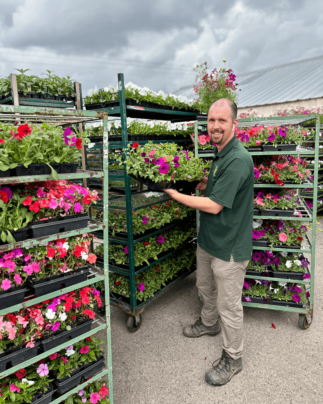 environmental designs employee holding up young Annual flowers while smiling