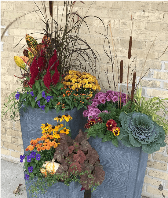 blue grey planter with flowers. tipple tiered standing planter with plastic evergreen flowers and plants