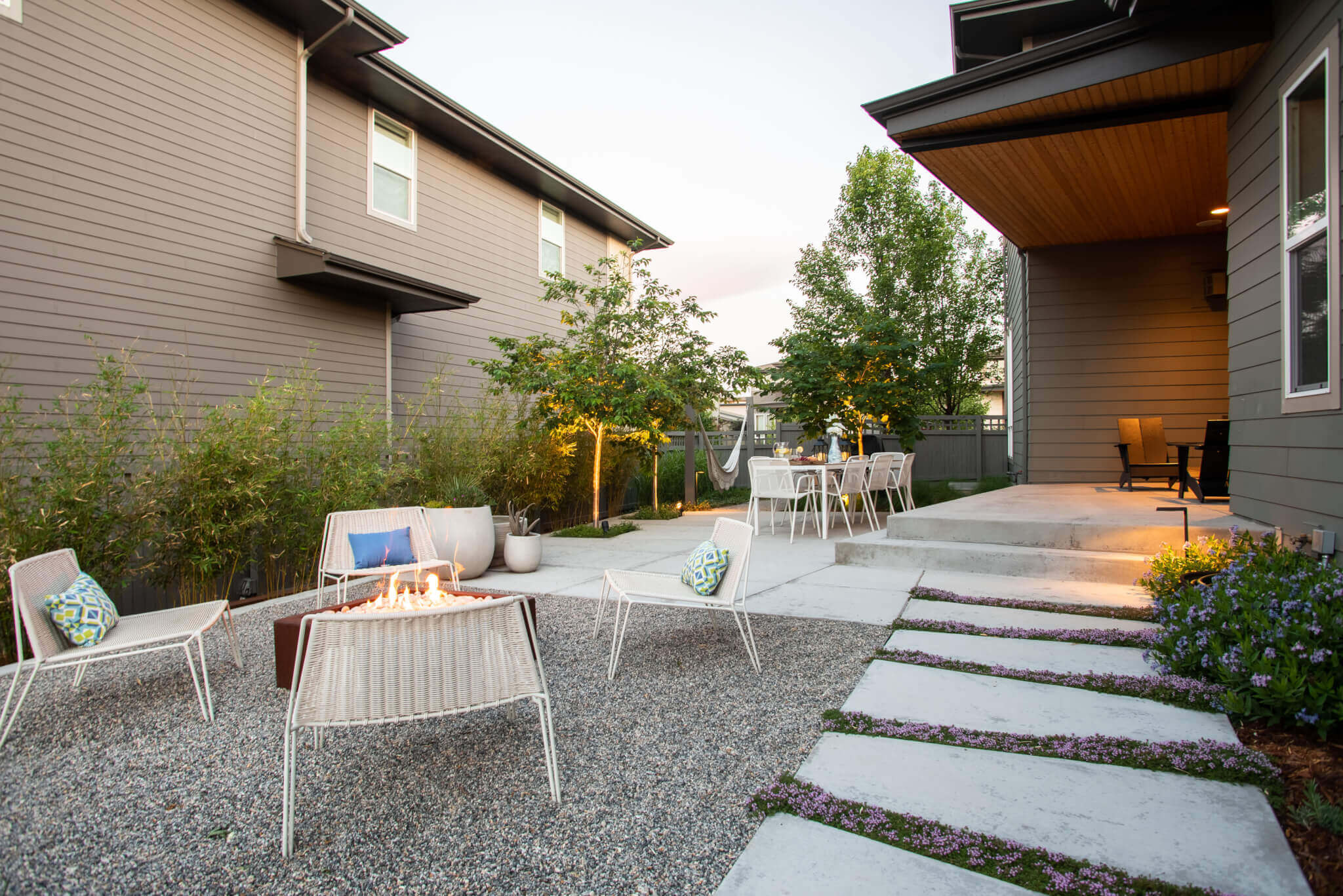 xeriscape back yard with fire pit, white gravel, concrete steps and white patio furniture