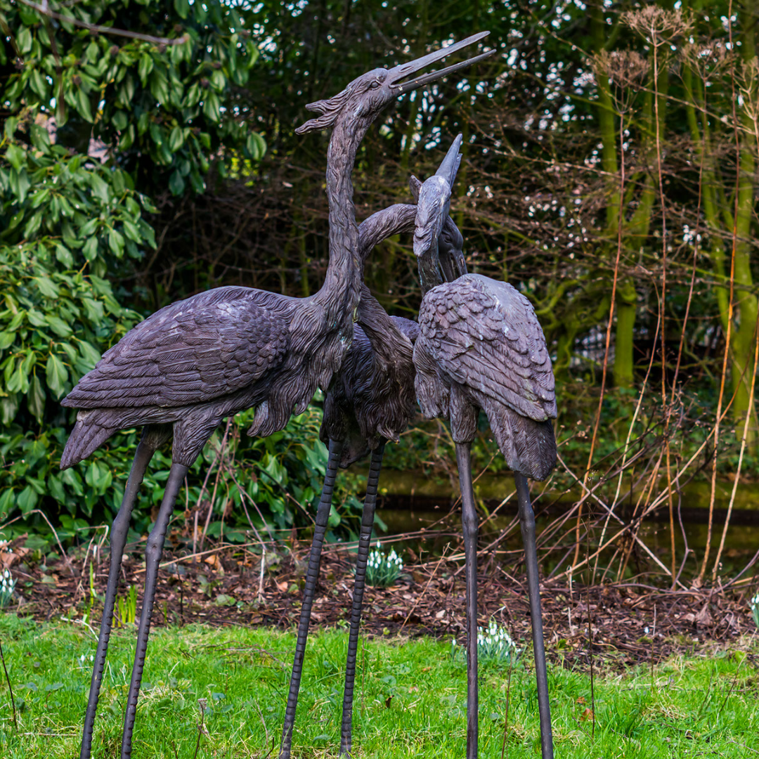 metal crane lawn ornaments in a grass field in the day