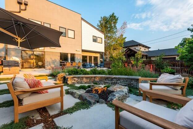 back yard xeriscape day time with a fire pit, boulders, and natural landscape. concrete stamped walkway with thyme 