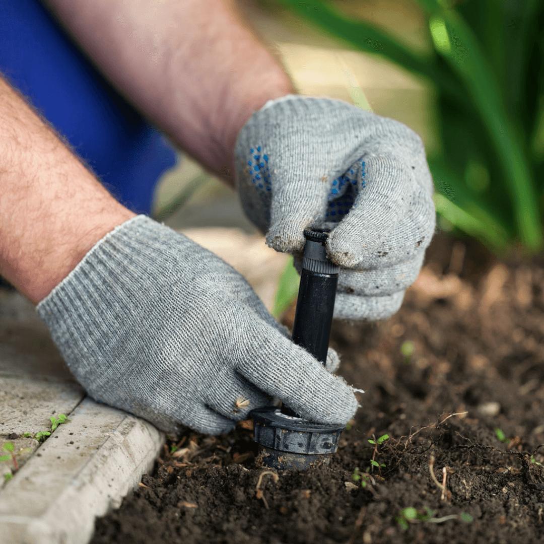 Smart Irrigation System installation closeup. Gloved hands installing sprinkler