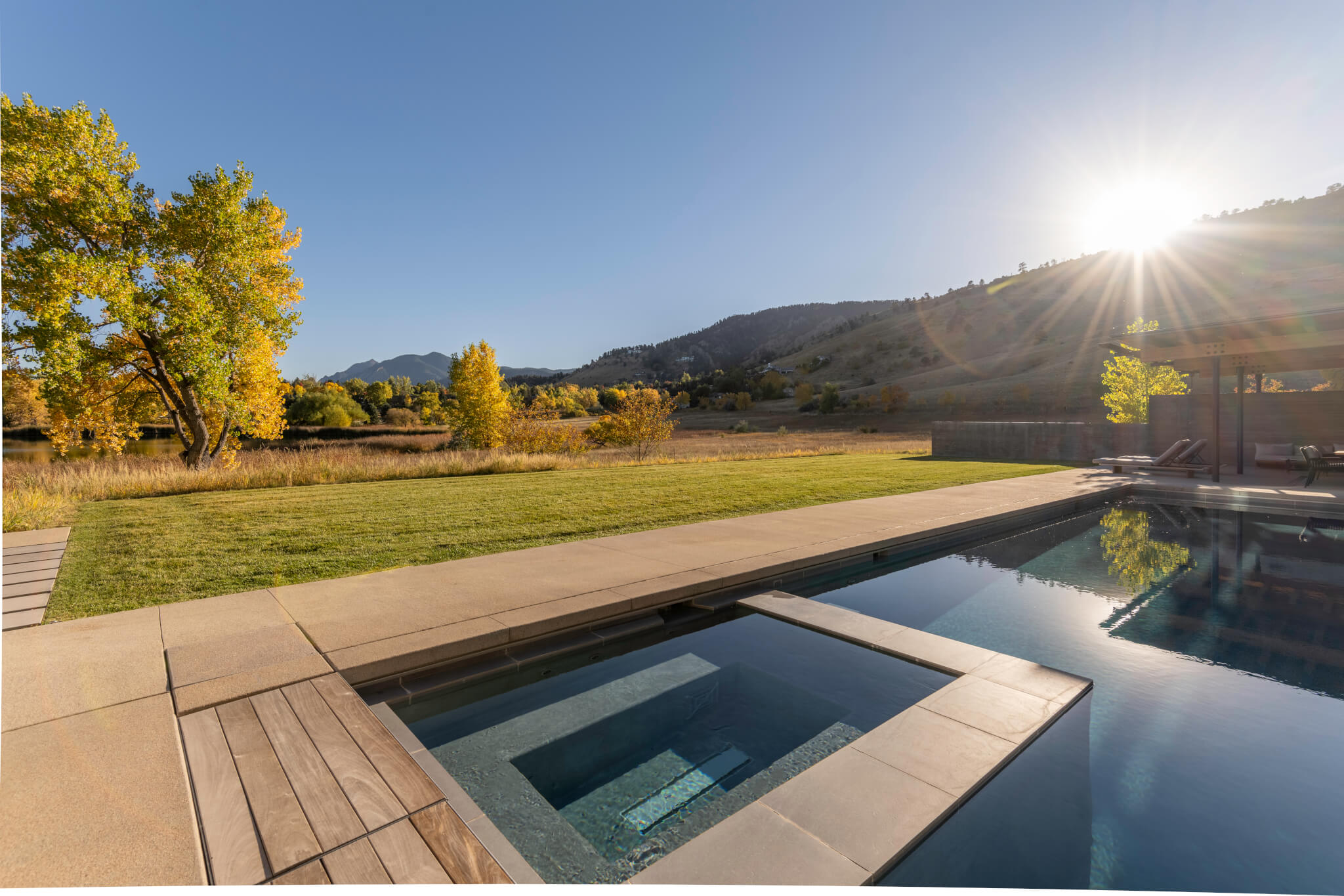 Outside patio surrounded with some chairs, tables, swimming pool and a beautiful sky view outside